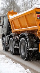 A snowplow truck works diligently to clear a road surrounded by a beautiful winter forest on a sunny day