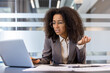 © Tetiana - Frustrated young african american business woman sitting in office at work desk with documents and looking at laptop screen in frustration with arms outstretched