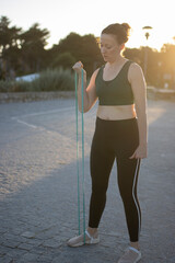 Wall Mural - Athletic woman performing biceps curl with resistance band outdoors