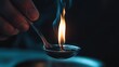 © Darunee - A close-up of a person holding a lit lighter under a metal spoon containing a liquid substance