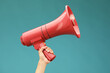 © New Africa - Woman holding megaphone speaker on blue background, closeup