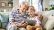 © GTNA73 - Smiling grandfather and grandson hug sitting on indoors cozy couch with digital tablet. Cuddle up day concept.