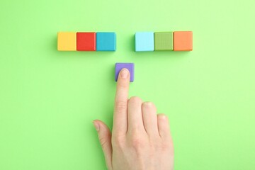 Sticker - Woman with colorful cubes on green background, top view