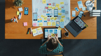 Top view of smart developer working on tablet and writing Ux Ui design for mobile phone interface at note. Manager design software program and sharing idea by using mind map. Top view. Convocation.