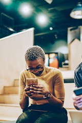 Overjoyed male and female hipster friends laughing at content from social networks using modern gadgets for networking, cheerful young multiracial colleagues having fun together on free time