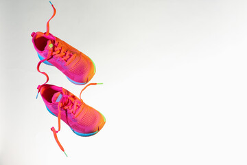 Wall Mural - Pair of stylish sneakers in air against white background in neon lights, space for text