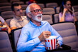 © Mediteraneo - Older man enjoying retirement in the cinema by watching a movie.