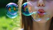 © Suphawan - Close-up of a young girl blowing soap bubbles outdoors, focusing on the colorful bubbles reflecting sunlight. Green grass in the background --chaos