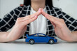 © RomanR - Small blue  toy car and female hand at office desk as insurance