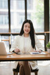 © Witoon - Beautiful Asian businesswoman focused on reviewing documents in a modern office.
