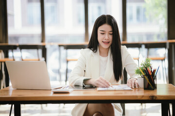 Asian accountant using laptop computer to analyze sales growth in global workplace market. Accounting concept.