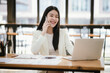 © Witoon - Beautiful Asian female accountant working with smartphone and laptop at her desk analyzing business reports and documents. Sending messages