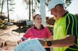 © Austockphoto - Apprentice builder laughing with  tradesman while looking at the blueprint on worksite