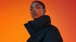© Amonthep - A captivating portrait of a young Black woman with short hair, confidently showcasing a stylish jacket against a vibrant background, highlighting modern fashion.