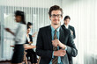 © InfiniteFlow - Portrait of happy businessman looking at camera with motion blur background of business people movement in dynamic business meeting. Habiliment