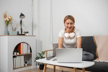 Young Woman Enjoying Online Entertainment Media on Laptop in Modern Living Room with Headphones