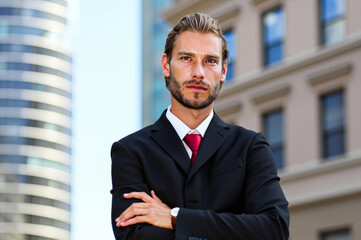 Serious businessman standing with arms crossed in  city center