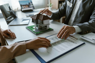 Real estate agent giving a house model to a client after signing a contract and receiving money