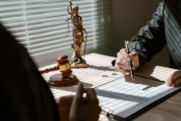 Lawyer is explaining a contract to a client before signing in the presence of a judge's gavel and themis statue