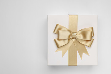 Canvas Print - Gift box with golden bow on light grey background, top view. Space for text