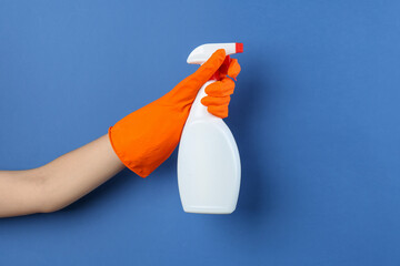 Wall Mural - Woman holding toilet cleaner in spray bottle on blue background, closeup