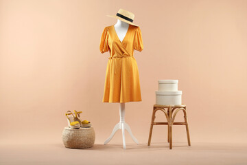 Mannequin with stylish dress, shoes and hat on beige background