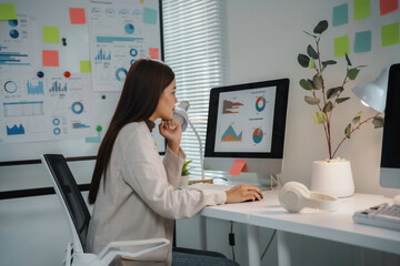 Businesswoman is analyzing financial charts and data on a computer screen, working on a project in the office