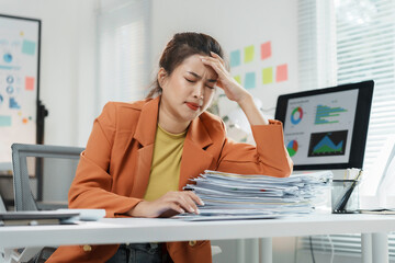 Young businesswoman holding her head with her hand, having a headache while working on a laptop at the office