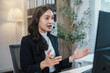©  NCST Studio - Asian businesswoman wearing headset is speaking on video call and gesturing while working on computer at office