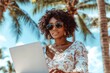 © alphaspirit - Young freelancer woman using laptop under palm trees