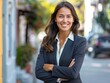 © zumrud - A professional young woman smiles confidently while standing in a bright business district