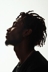 Profile of a young man with dreadlocks against a bright background in a minimalistic setting