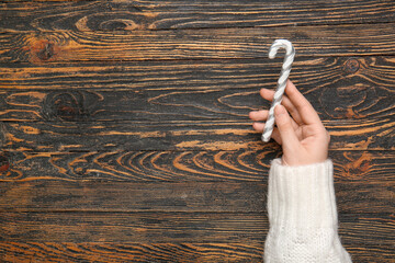 Wall Mural - Female hand with beautiful Christmas decoration on wooden background, closeup