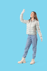 Wall Mural - Young woman in winter clothes on blue background