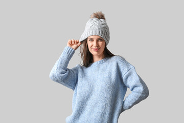 Wall Mural - Young woman in winter clothes on light background