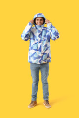 Poster - Young man in warm jacket on yellow background