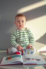 Early childhood development concept. Portrait of cute little boy reading the book.