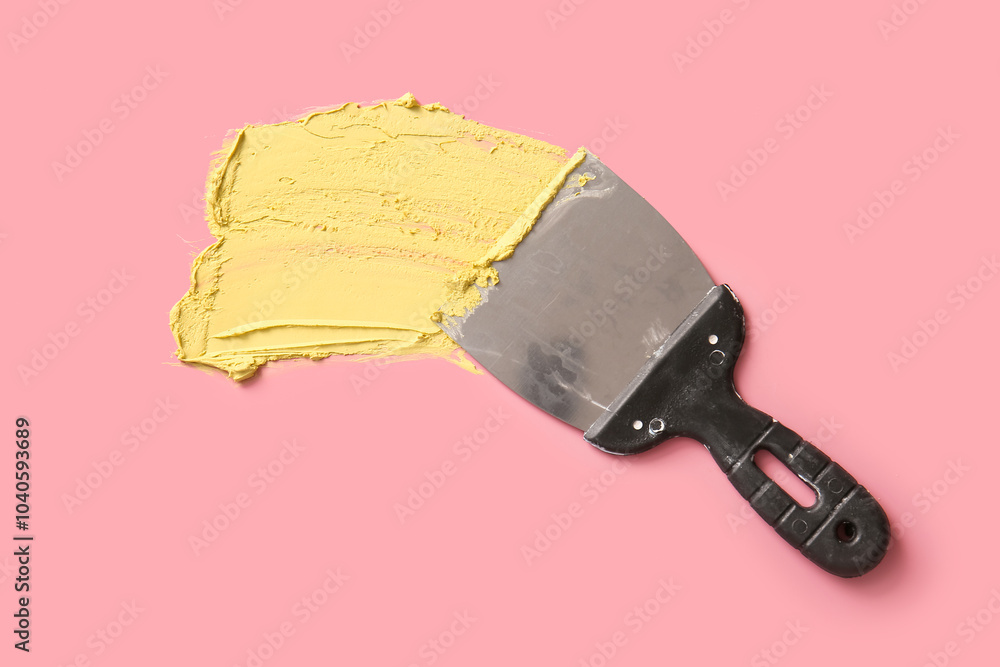 Putty knife on pink background