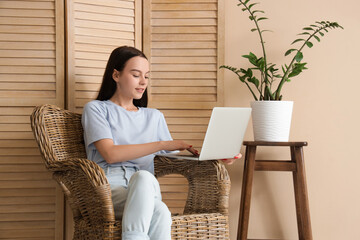 Poster - Teenage girl using laptop in wicker armchair at home