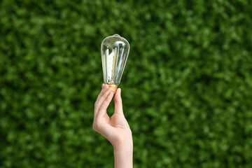 Woman with light bulb outdoors, closeup. Green Energy concept