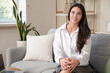 © Pixel-Shot - Pretty young businesswoman sitting on sofa at home