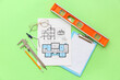 © Pixel-Shot - Architect's supplies with eyeglasses and house plan on green background