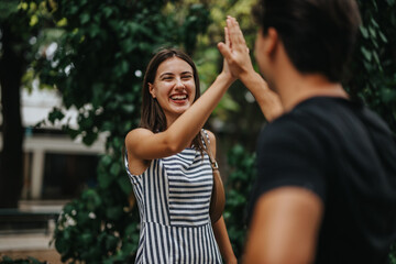 Two smiling friends give a high five, celebrating their friendship outdoors in a lush green park. The scene captures joy, connection, and togetherness.