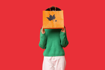 Wall Mural - Young Asian woman with shopping bag on red background