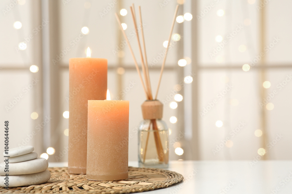 Burning candles, spa stones and reed diffuser on light background