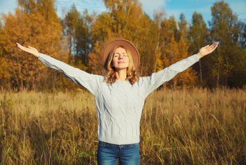 Wall Mural - Happy young smiling woman in autumn park, joyful girl enjoying warm sunny weather, fall season