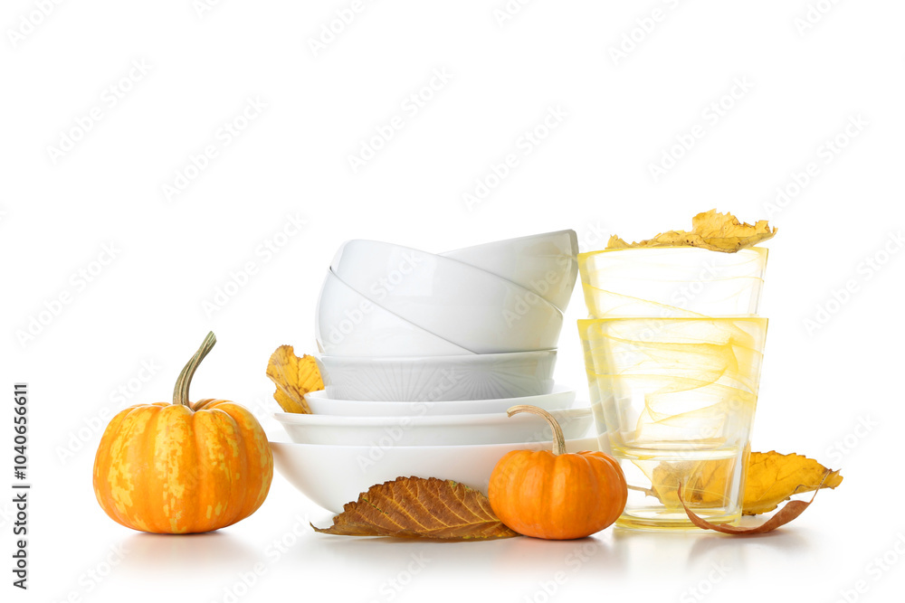 Stack of dishes with autumn decor and pumpkins on white background