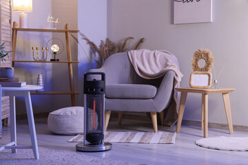 Interior of room with stylish armchair and modern electric heater at evening