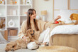 © Pixel-Shot - Beautiful young happy woman with cute Cocker Spaniel dog and cup of green tea on tray at home