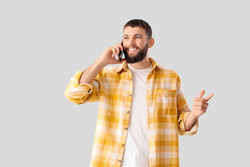 Wall Mural - Handsome young happy man talking by mobile phone on grey background